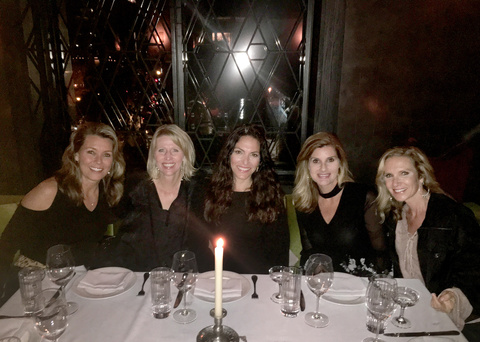 Regina Carls with college friends seated at a table with a white tablecloth