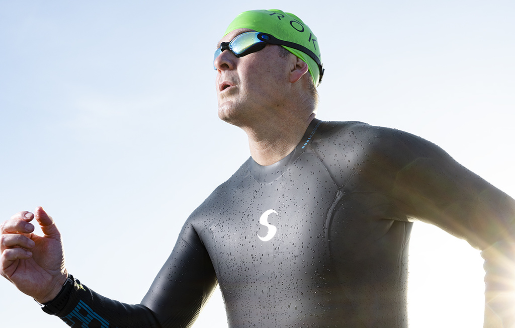 Bill Smith in a wetsuit, green swim cap, and goggles