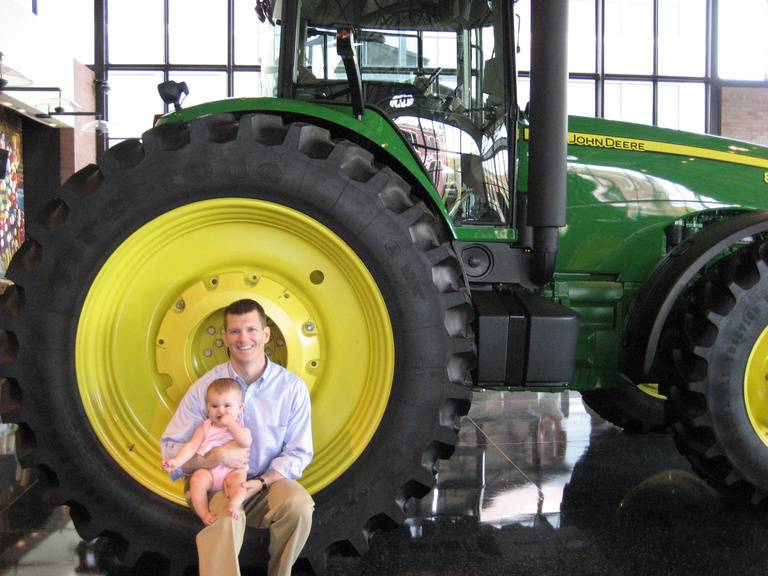 Mark Ruedy with baby and John Deere tractor. 