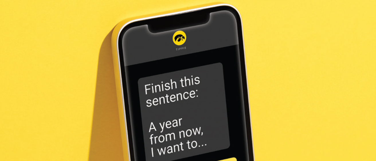 Phone screen with text: Finish this sentence: A year from now, I want to... And a reply bubble indicating someone is writing back..