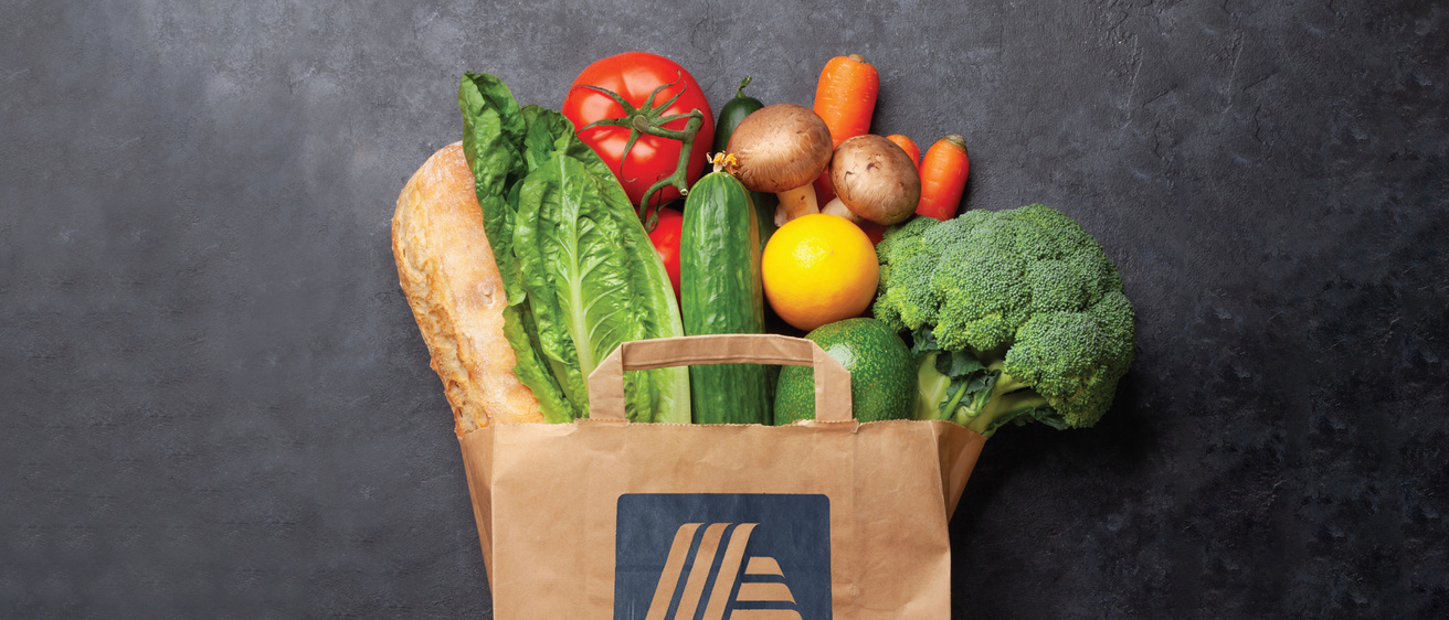 Paper grocery bag with ALDI logo and food sticking out of the top. 