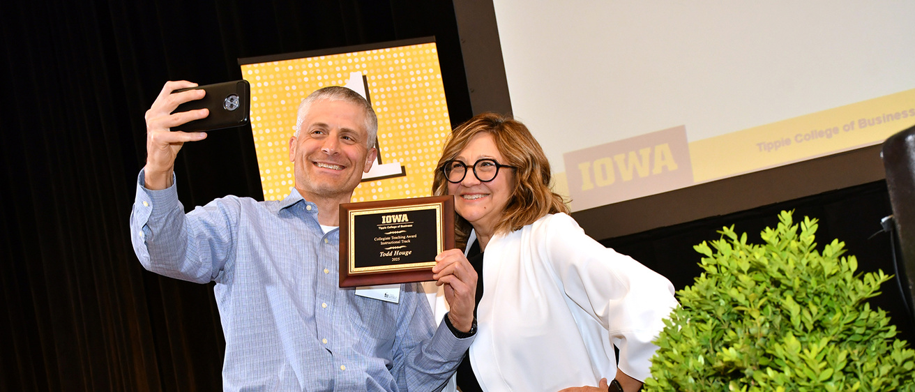 Todd Houge posing with a teaching award plaque with Dean Amy Kristof Brown