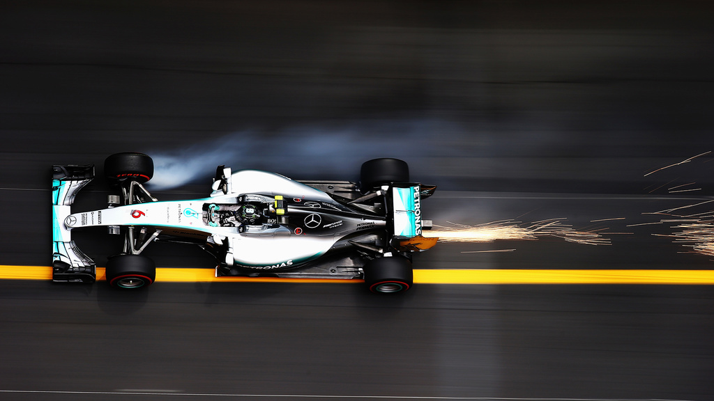 F1 car leaves sparks as it speeds down a track with a yellow painted line.